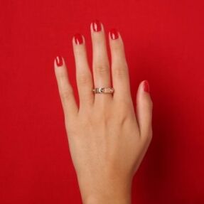 main sur fond rouge avec bague Louis Vuitton d'occasion