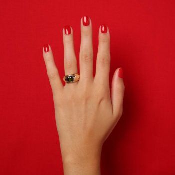 main sur fond rouge avec bague Boucheron d'occasion
