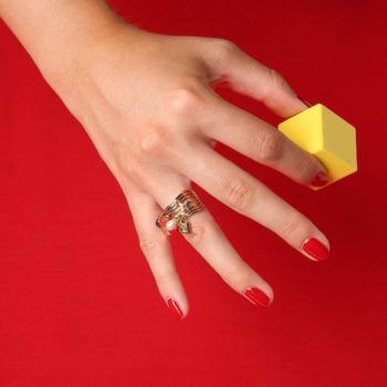 main sur fond rouge avec bague Louis Vuitton d'occasion